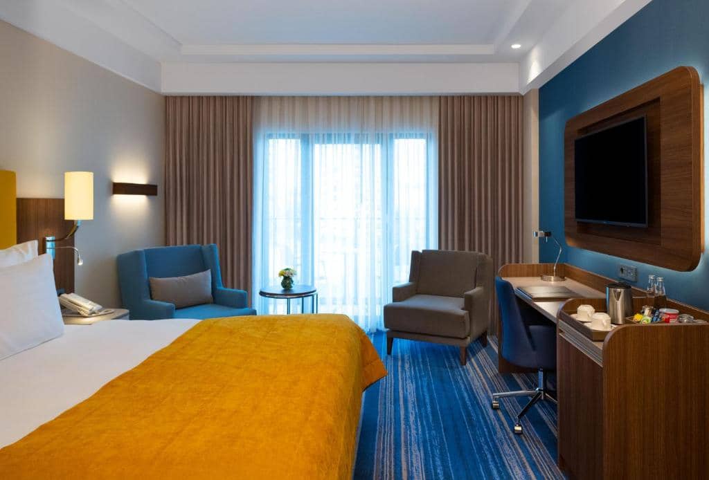 Mövenpick Hotel Istanbul Asia Airport - a hotel room with a bed and chairs and a television at Mövenpick Hotel Istanbul Asia Airport in Istanbul