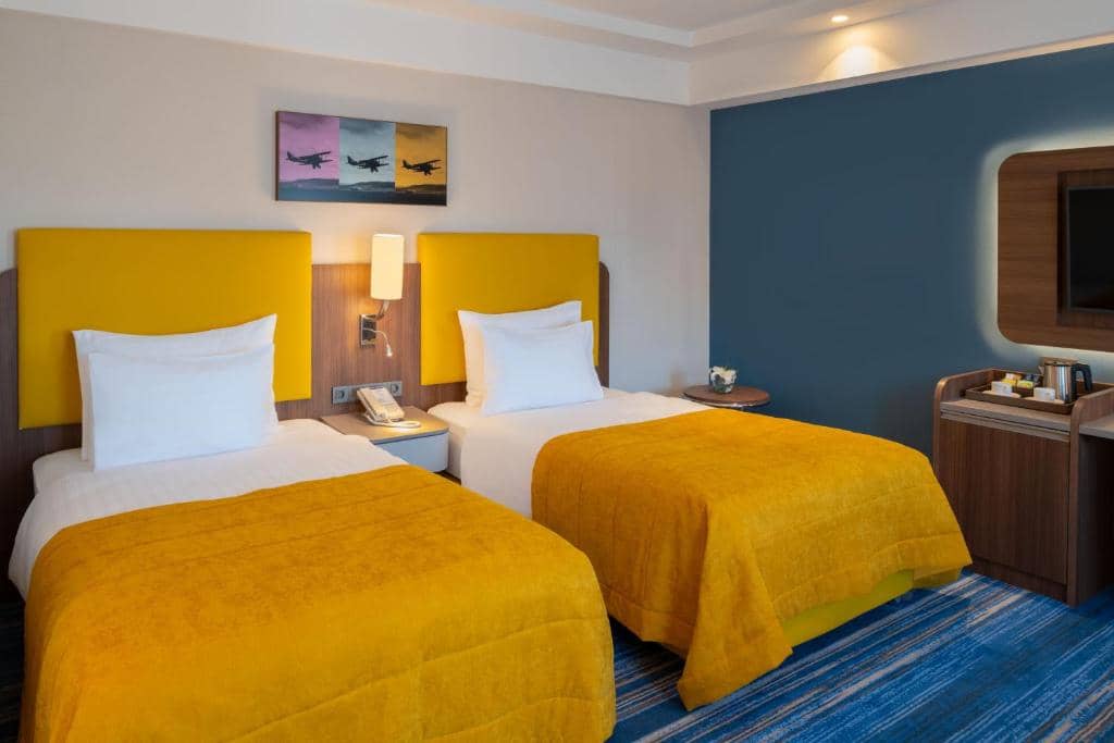 Mövenpick Hotel Istanbul Asia Airport - a hotel room with two beds and a tv at Mövenpick Hotel Istanbul Asia Airport in Istanbul
