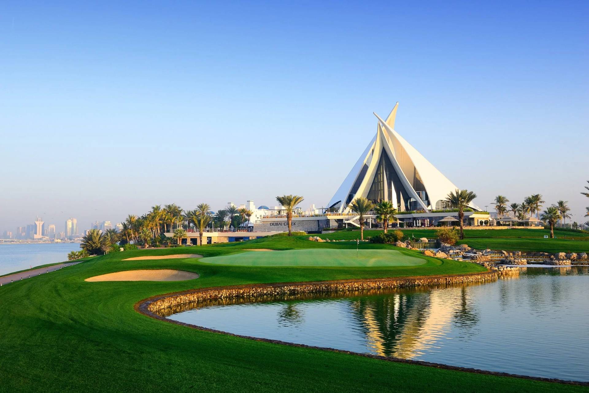 Dubai Creek Golf & Yacht Club, lush greens, reflecting water, clear sky.