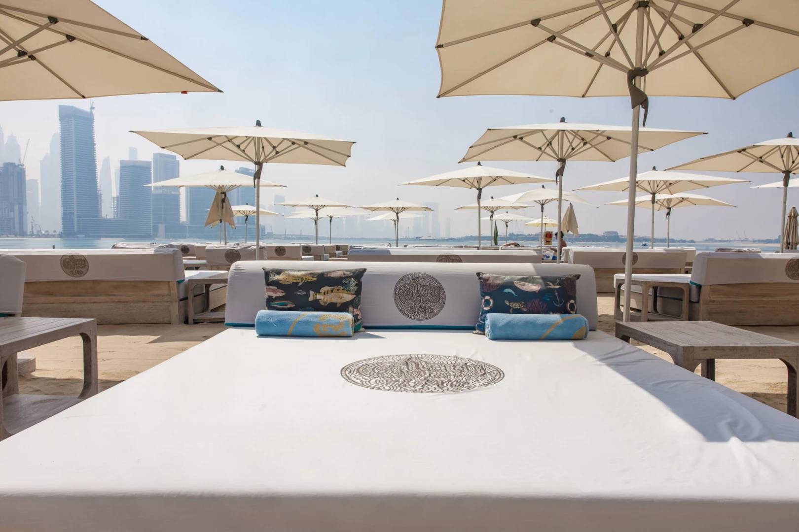 Gallery 7/40 Dubai beach seating with umbrellas and skyline view.