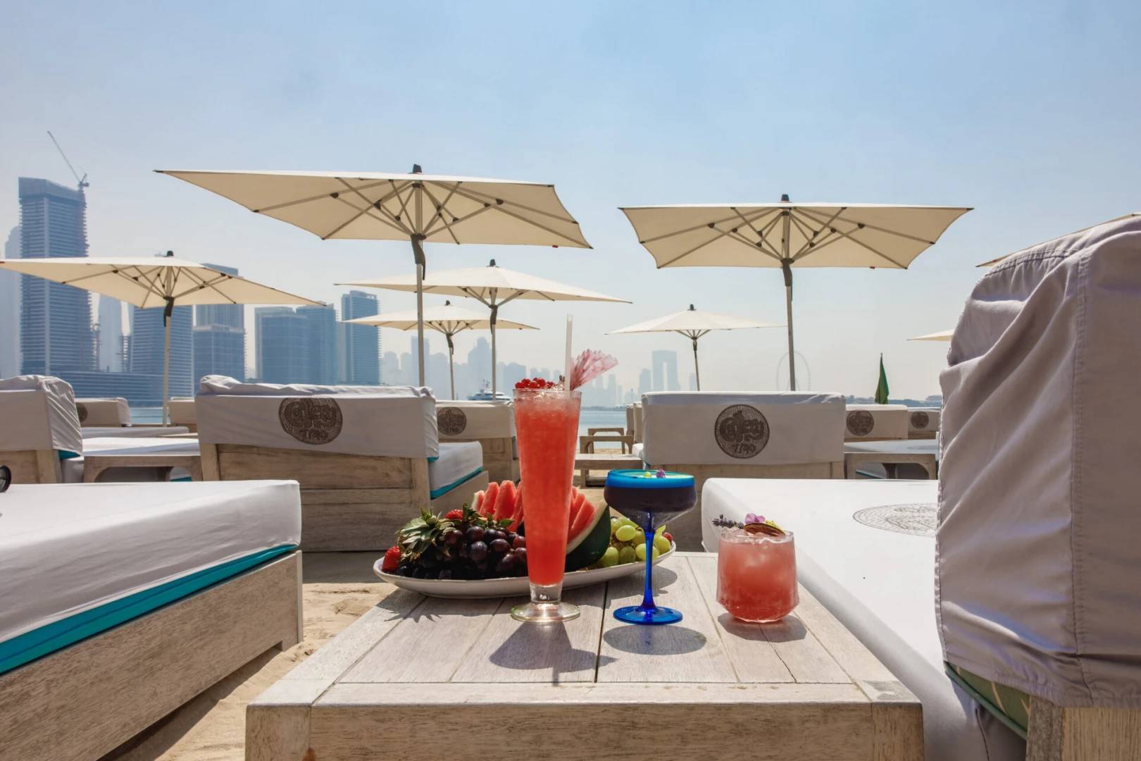 Gallery 7/40 Dubai beachside lounge with drinks and city skyline.