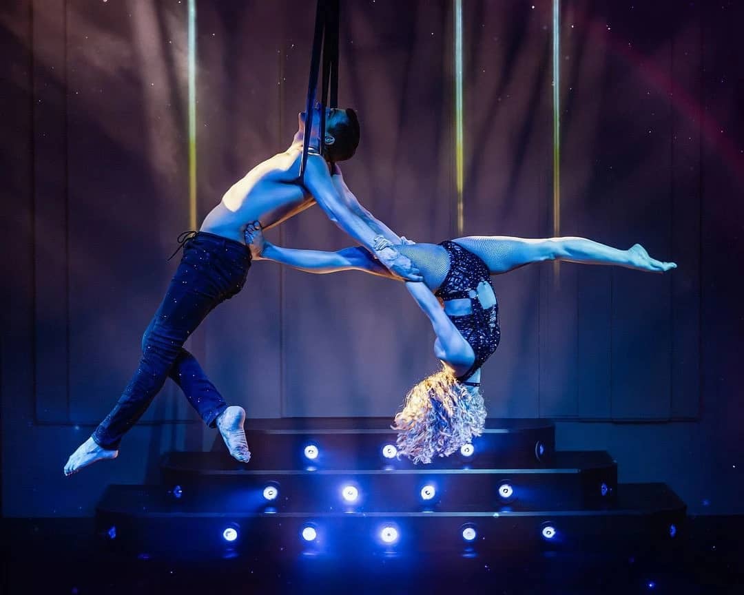 Aerial performers at DREAM Dubai Dinner Show, vibrant stage lighting.
