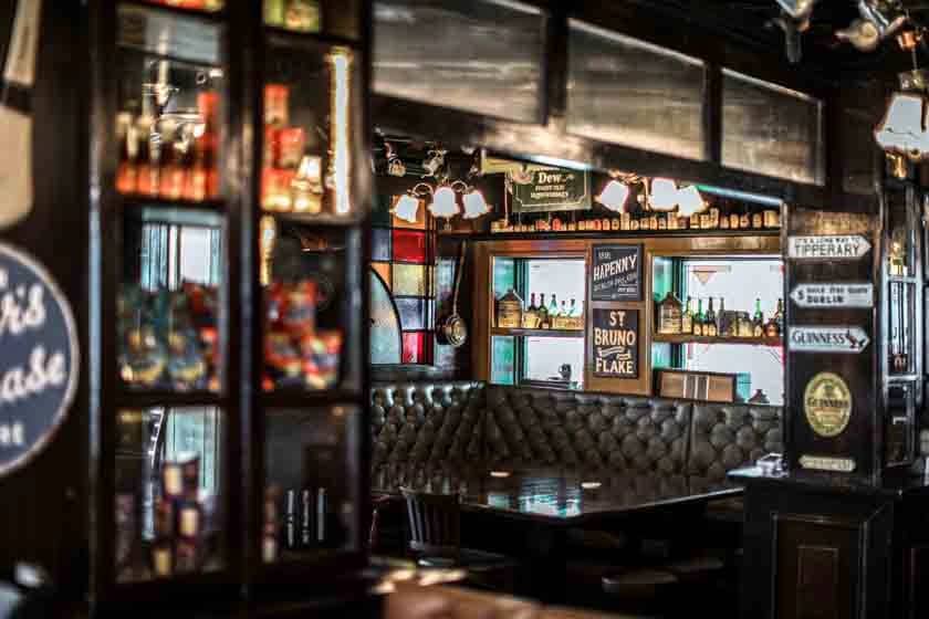 Dimly lit pub corner with tufted seating and vintage signs, Dubai.