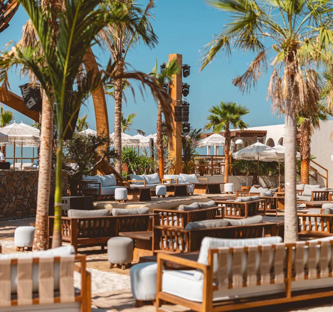 Outdoor lounge at Be Beach DXB, Dubai with palm trees.