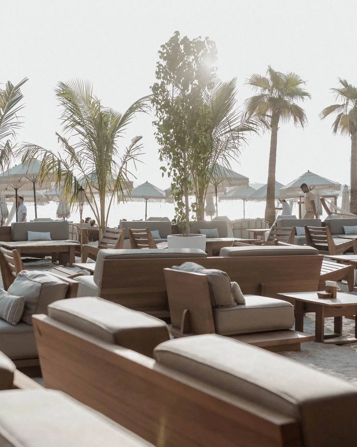 Outdoor seating at Surf Club Dubai with palm trees and umbrellas.