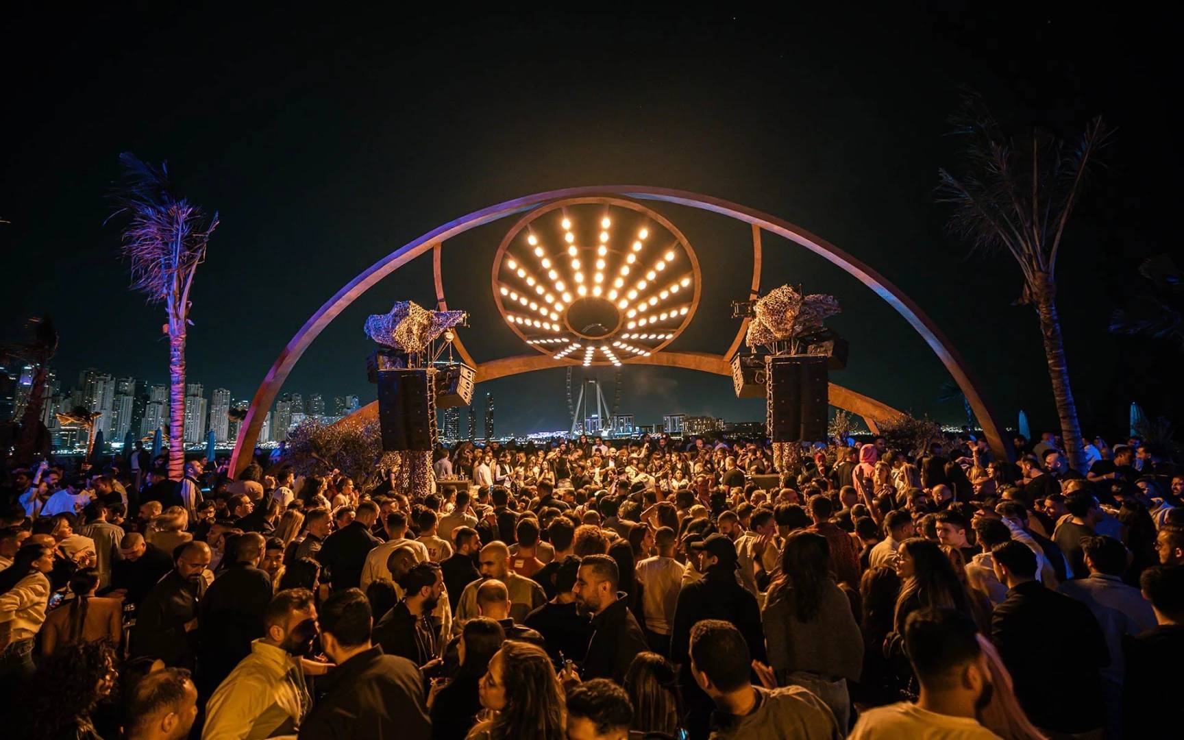 Crowded night event at Be Beach DXB, Dubai with city skyline.