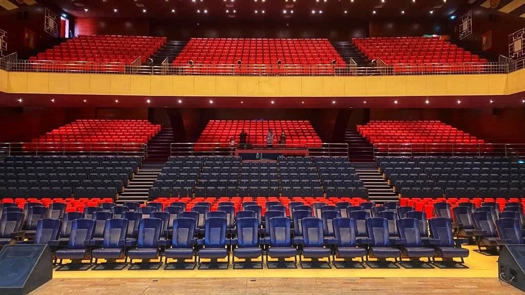 Sheikh Rashid Auditorium seating, Dubai, with red and blue chairs.