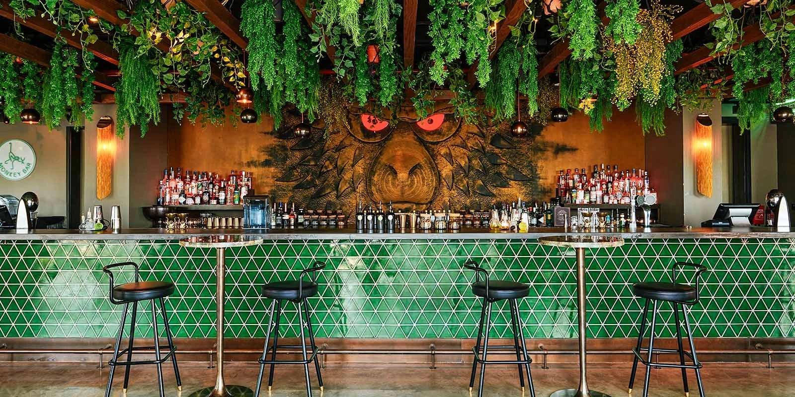 Monkey Bar Dubai interior with green tiles and hanging plants.