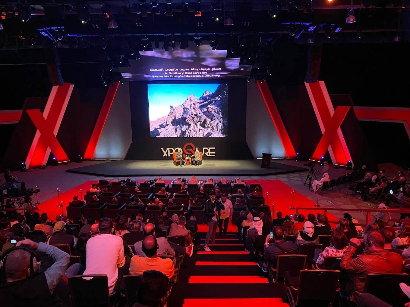 Audience at Expo Centre Sharjah conference with large screen display.