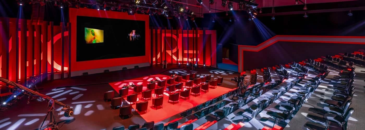 Expo Centre Sharjah auditorium with red lighting and seating arrangement.