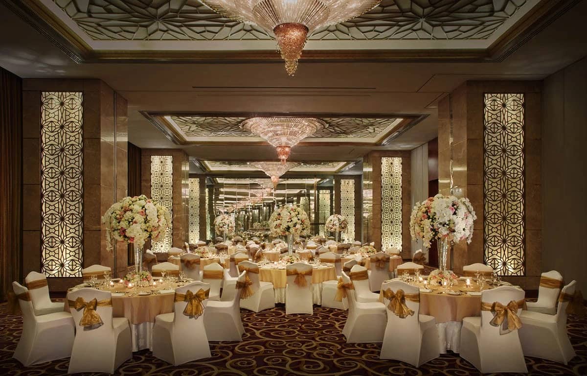 Elegant ballroom at The Meydan Hotel, Dubai, with floral centerpieces.