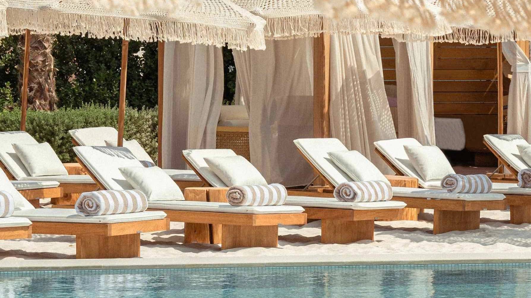 Kyma Beach Dubai sun loungers by poolside with cabanas.