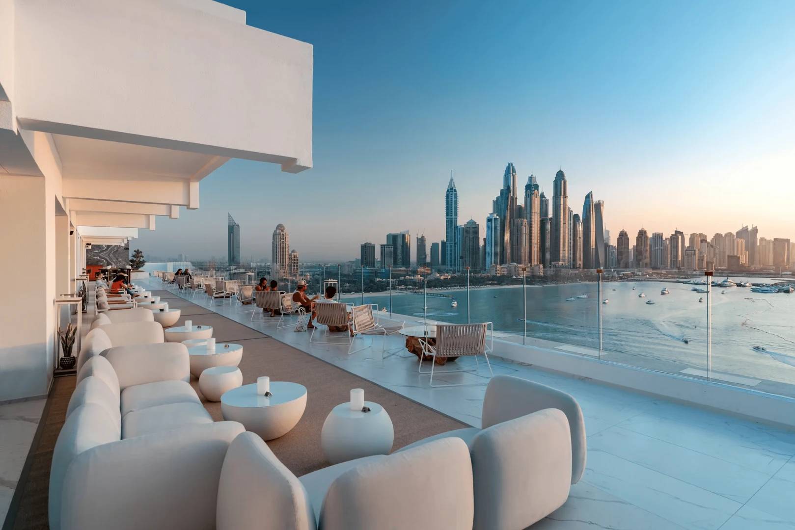 Elegant rooftop seating with panoramic Dubai skyline at sunset.