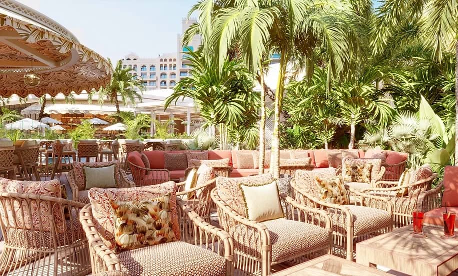 Outdoor seating at Maison de La Plage, Dubai, surrounded by palm trees.