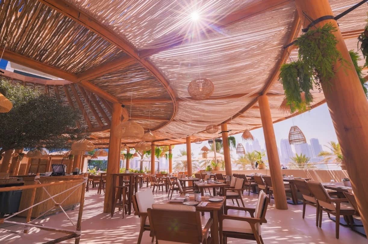 Ula Dubai Beach Club outdoor seating with wooden decor and city view.