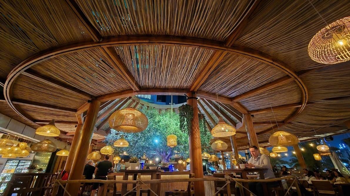 Ula Dubai Beach Club interior with bamboo ceiling and hanging lights.