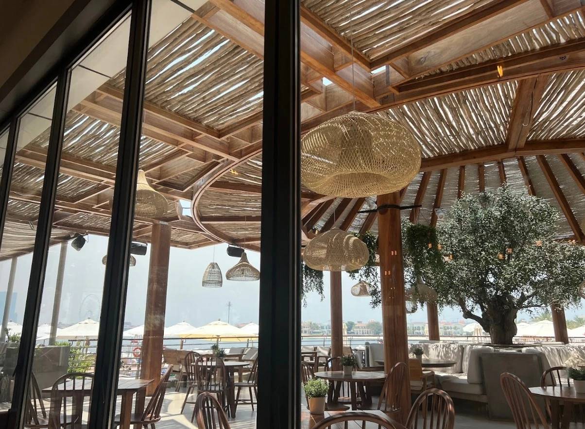 Ula Dubai Beach Club outdoor seating with wooden decor and sea view.