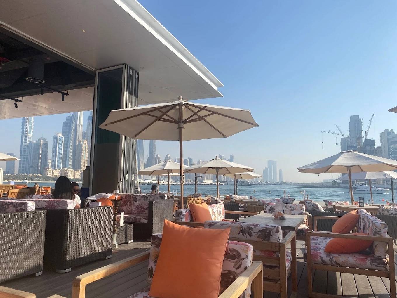 Outdoor seating at Orange Chameleon Restaurant & Lounge, Dubai waterfront view.