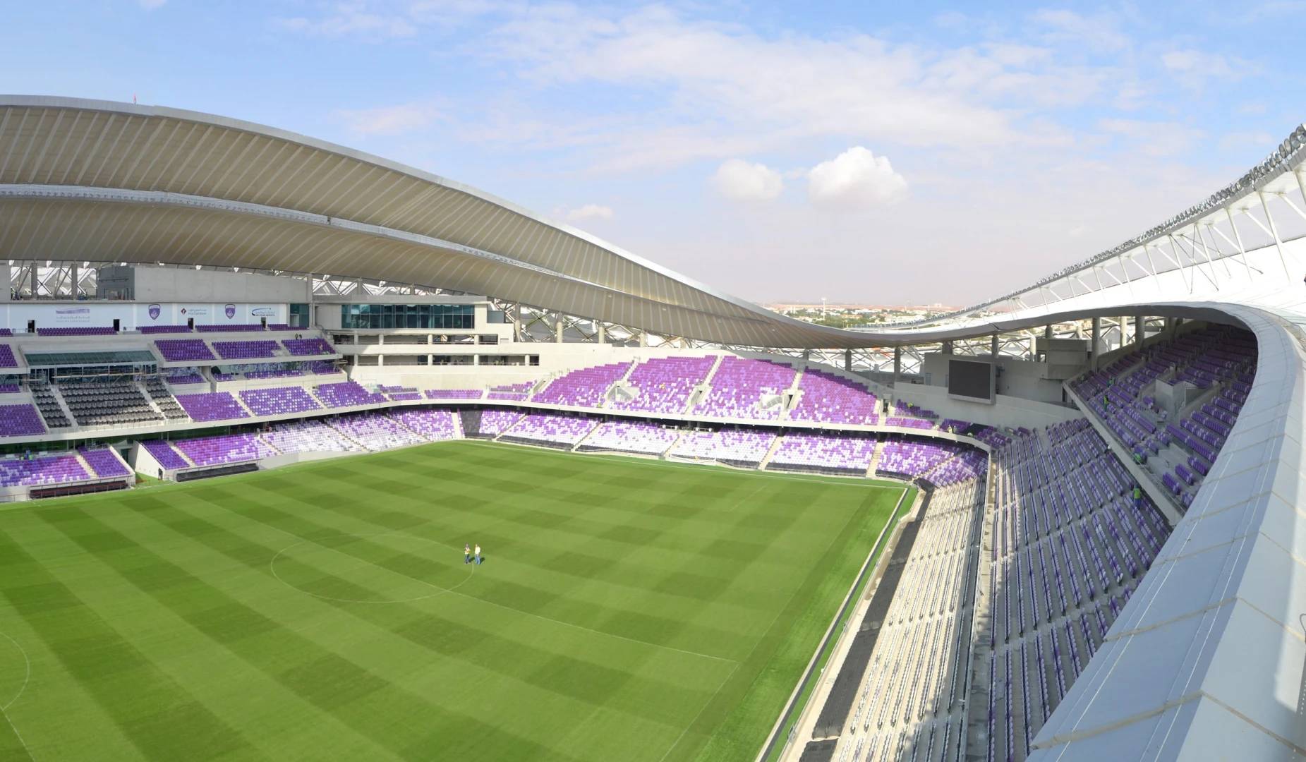 Hazza Bin Zayed Stadium in Al Ain, empty with green field.