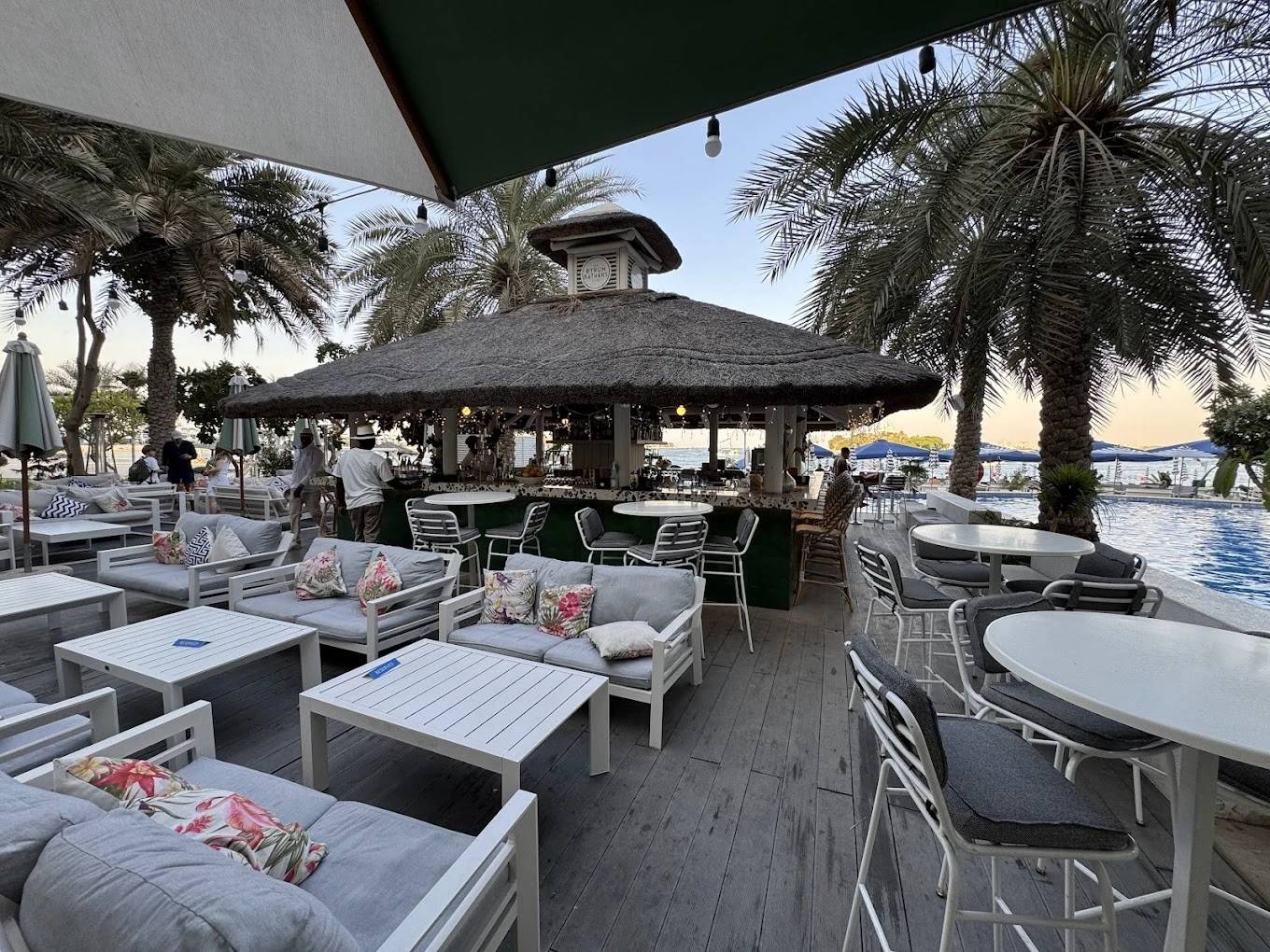 Outdoor seating at The Byron Bathers Beach Club, Dubai, with palm trees.