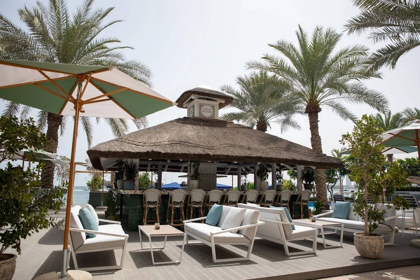 Outdoor seating at The Byron Bathers Beach Club, Dubai with palm trees.