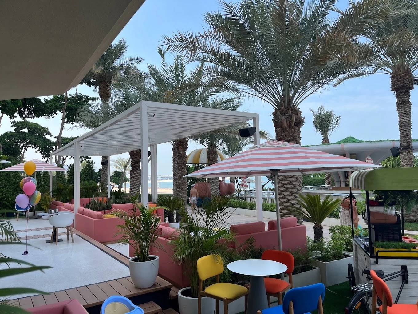 Outdoor seating at Peaches & Cream Beach Restaurant, Dubai with palm trees.