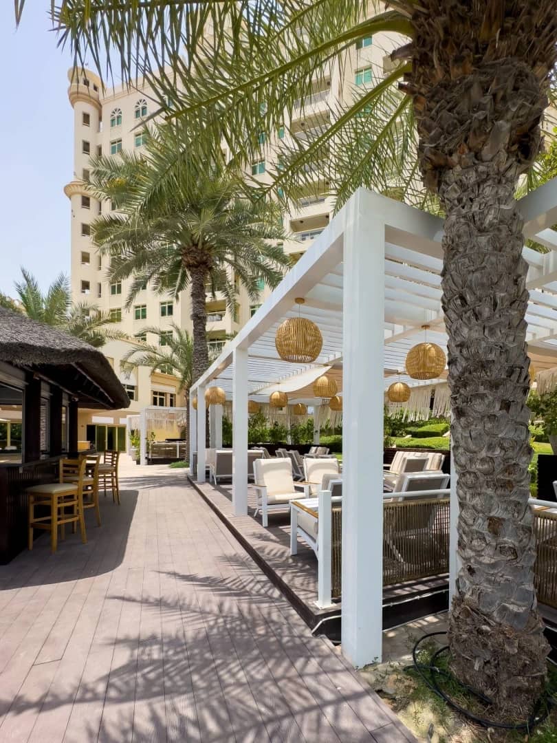 Outdoor seating with palm trees at Cabana On The Beach, Dubai.