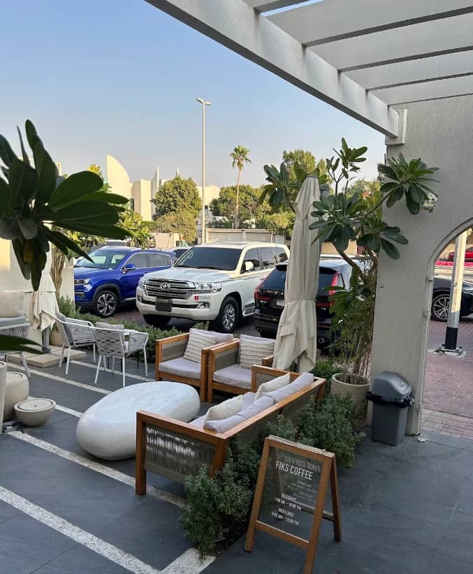 Outdoor seating at Fiks Coffee Umm Suqeim, Dubai with parked cars.