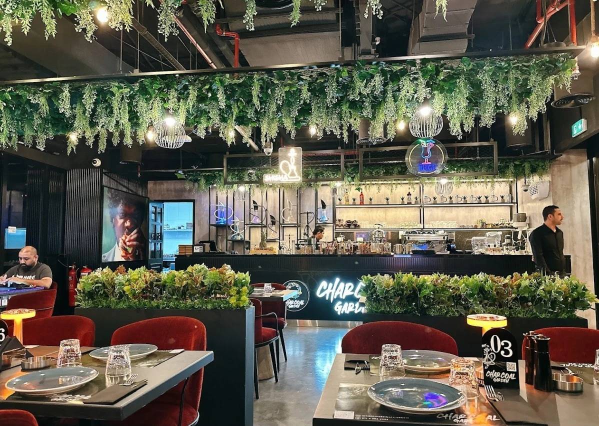 Charcoal Garden Restaurant Dubai, lush greenery, modern decor, dining tables.