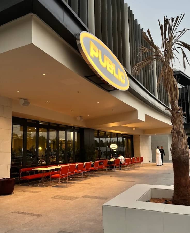 PUBLIC Restaurant Riyadh entrance with outdoor seating and palm tree.