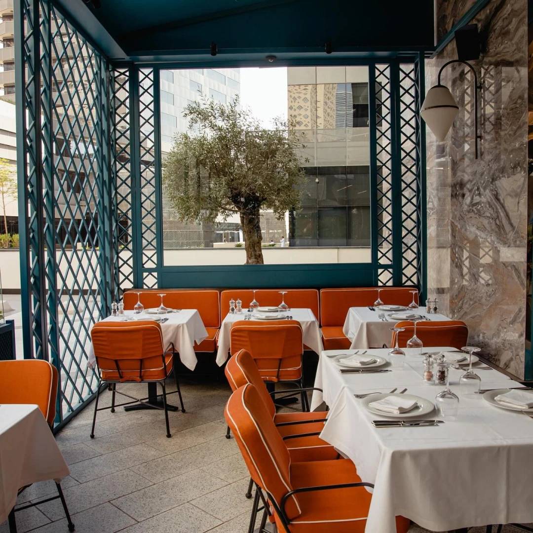 Outdoor dining area at Il Baretto Restaurant, Riyadh with orange chairs.