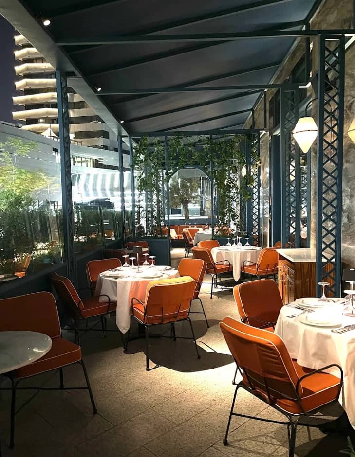 Outdoor dining area at Il Baretto Restaurant, Riyadh, with orange chairs.