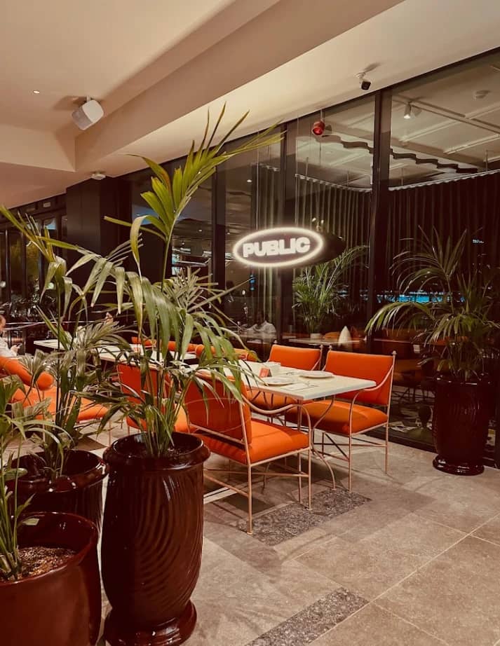 PUBLIC Restaurant Riyadh, elegant dining area with orange seating and plants.