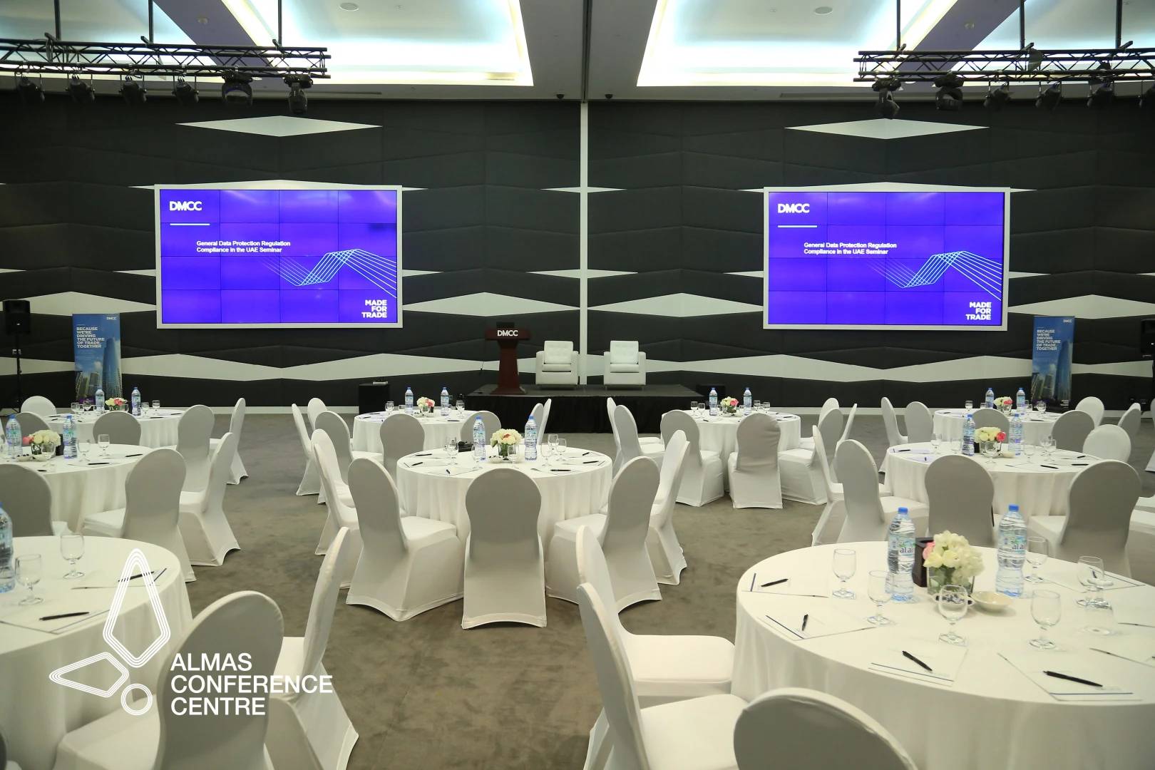 Almas Conference Centre Dubai, round tables, stage with screens.