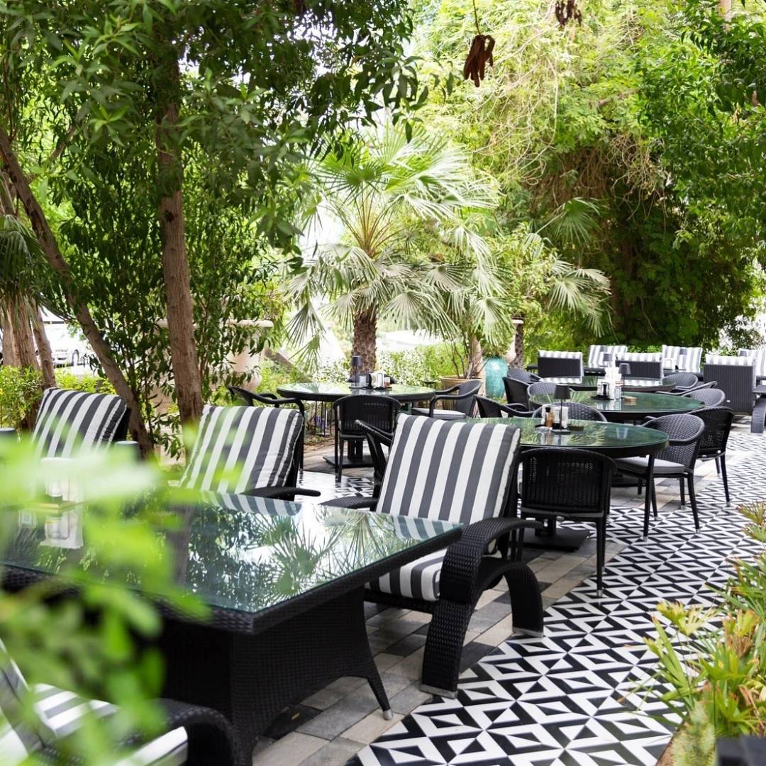 Outdoor seating at Twisted Olive & Naama’s Garden, Doha, lush greenery.