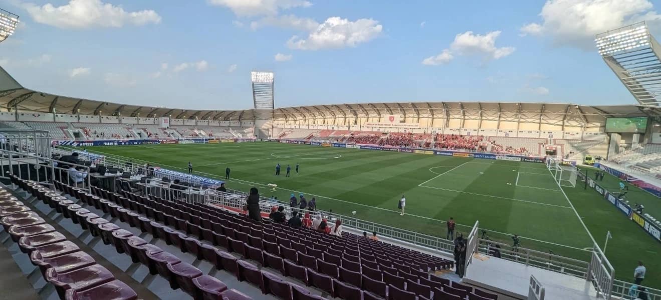 Abdullah Bin Khalifa Stadium in Doha, empty seats, clear sky.