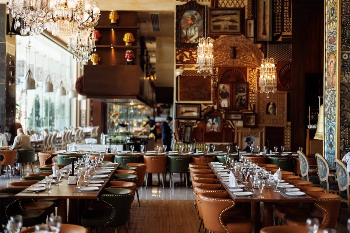 Elegant dining area at Tanatan Dubai with chandeliers and artwork.