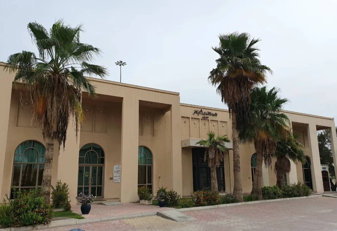 Fatima Kanoo Hall exterior with palm trees, Manama.