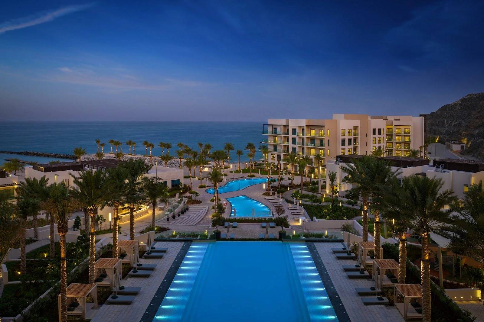Illuminated pool and resort buildings at Address Beach Resort Fujairah, Fujairah, UAE