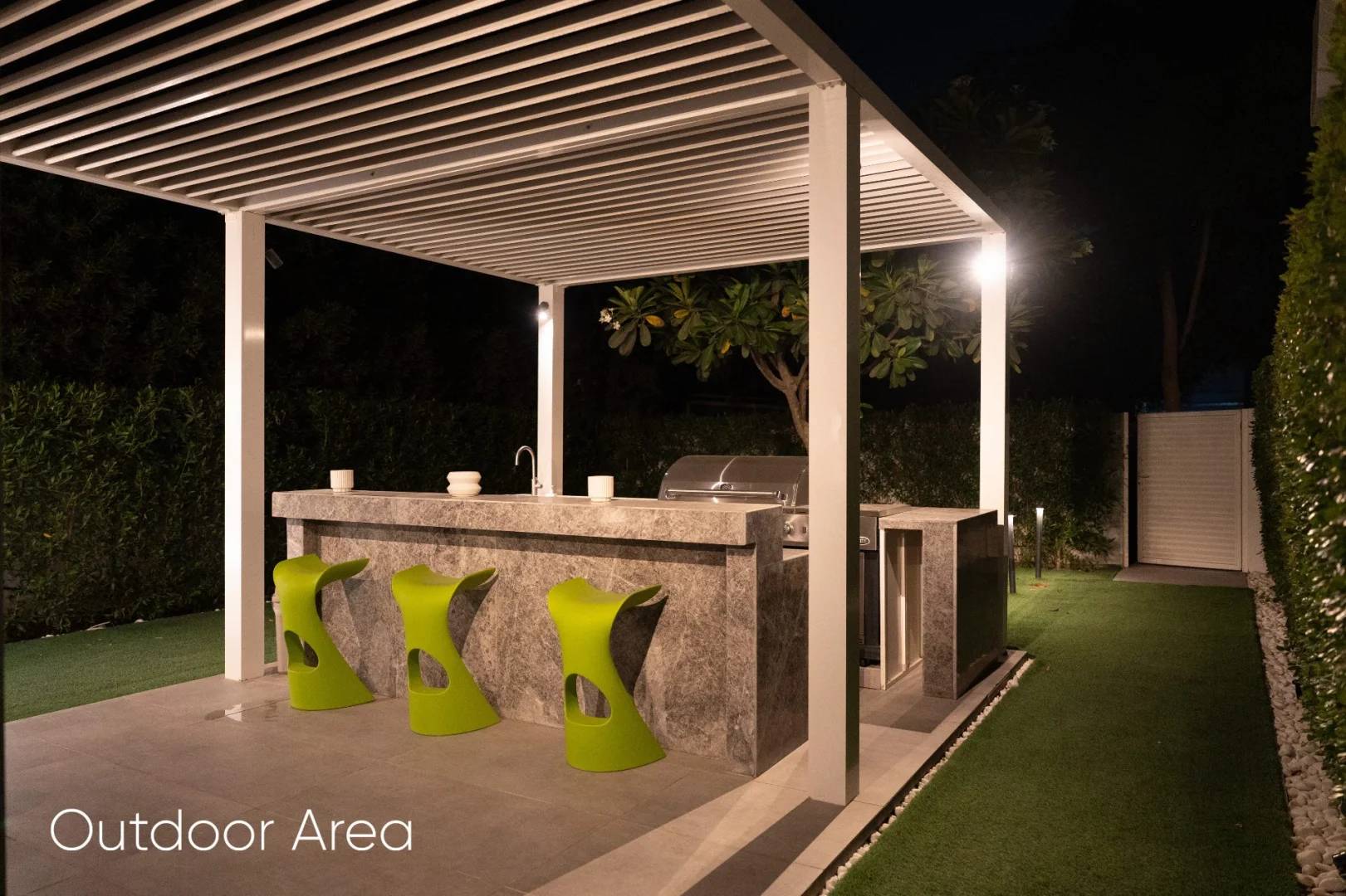 Outdoor area with bar and green chairs at Aureum Club, Dubai, UAE
