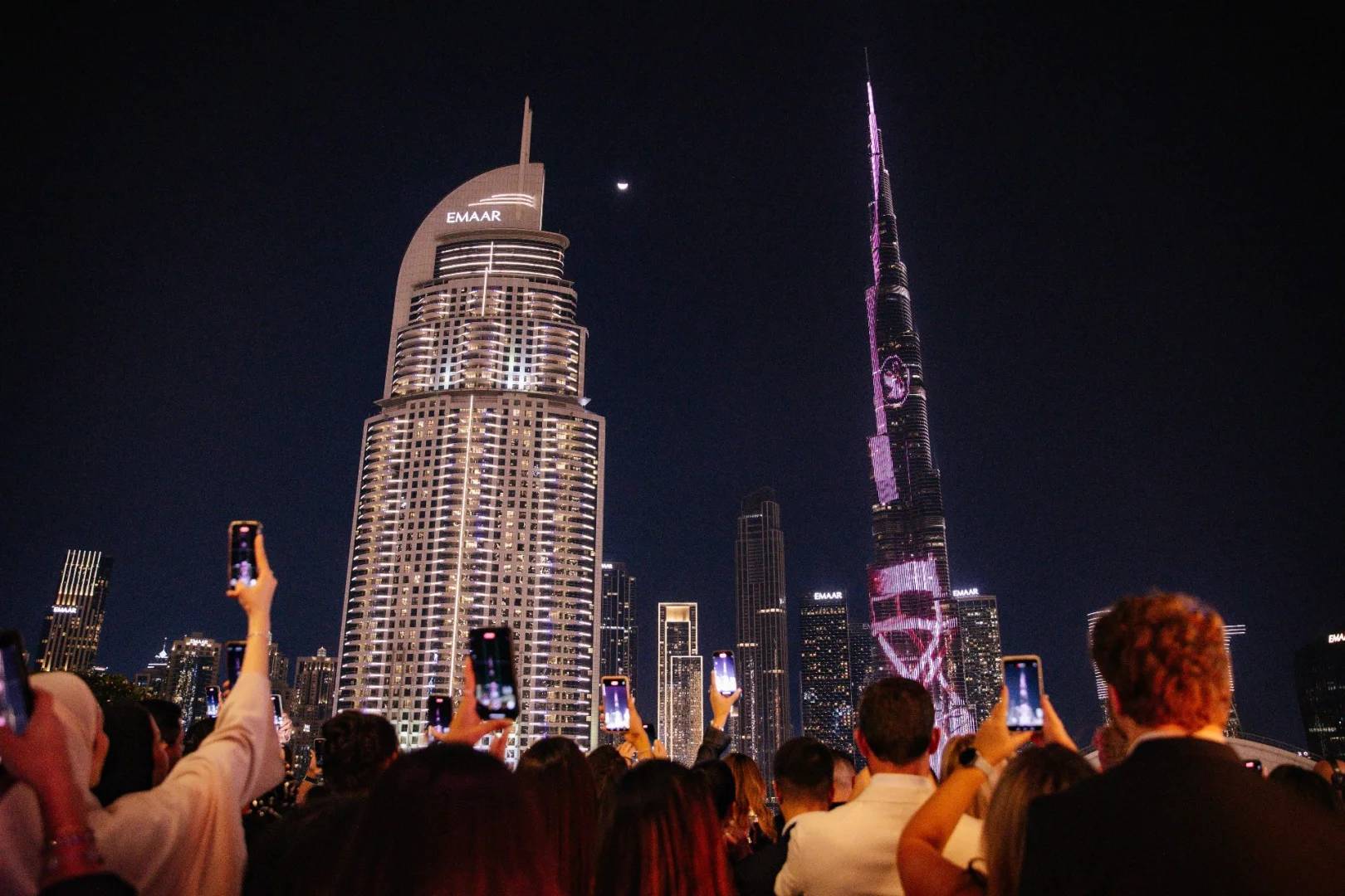 Crowd taking photos of illuminated skyscrapers at Nazcaa Japanese Peruvian Dubai, UAE.