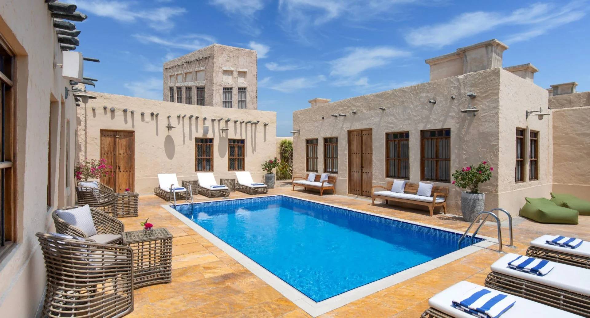 Outdoor pool area with lounge chairs at Souq Al Wakra Hotel, Doha, QATAR
