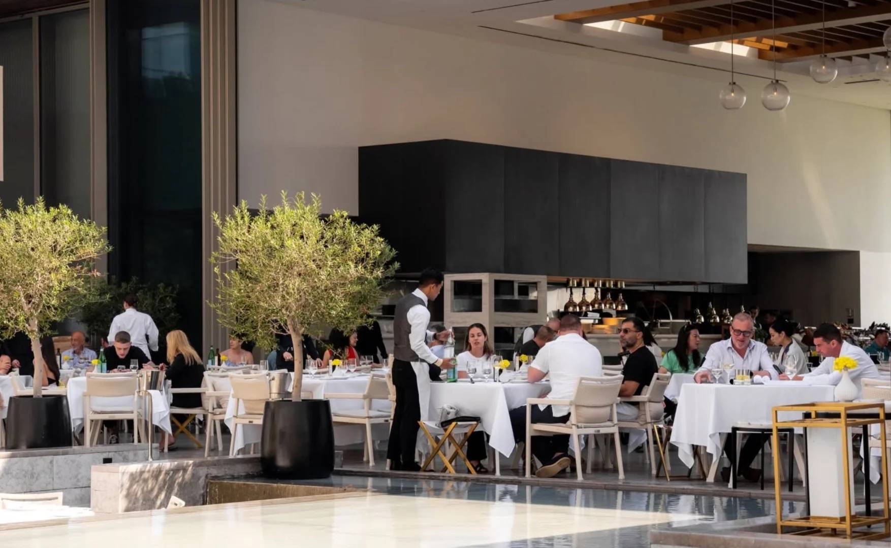 Outdoor dining area at Estiatorio Milos Dubai, Dubai, UAE with guests and staff.