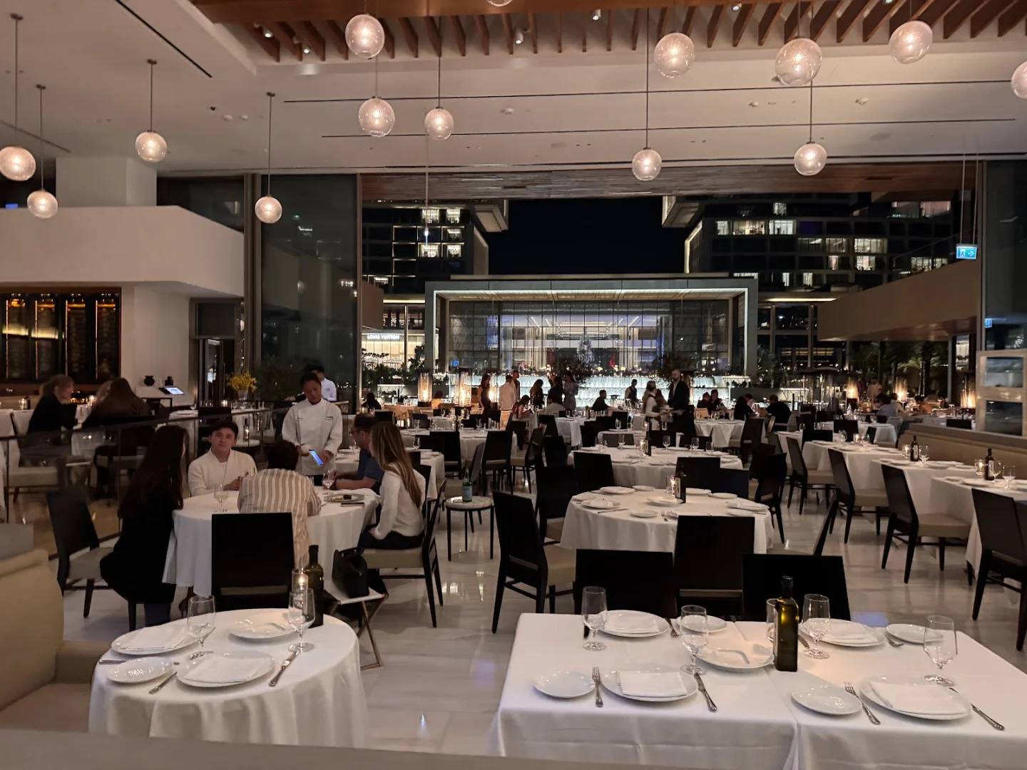 Elegant dining area with round tables at Estiatorio Milos Dubai, Dubai, UAE.