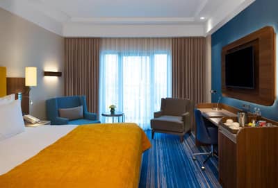 Mövenpick Hotel Istanbul Asia Airport - a hotel room with a bed and chairs and a television at Mövenpick Hotel Istanbul Asia Airport in Istanbul