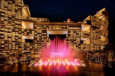 Illuminated Atlantis The Royal Dubai with vibrant fountain display at night.