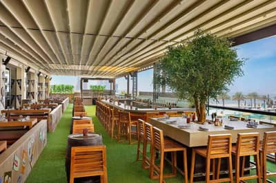 Outdoor dining area at Hilton Dubai Palm Jumeirah, overlooking the beach.
