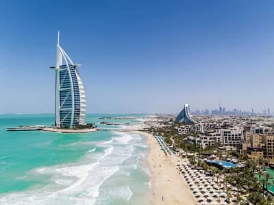 Jumeirah Beach Hotel and coastline in Dubai, clear blue sky.