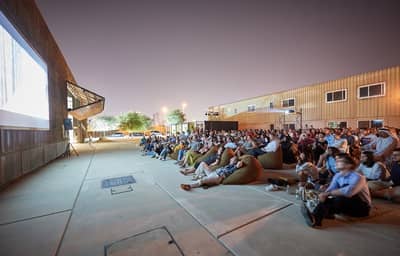 Nighttime outdoor film event at Cinema Akil, Dubai, with audience seated.