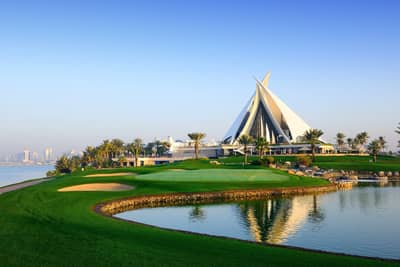 Dubai Creek Golf & Yacht Club, lush greens, reflecting water, clear sky.